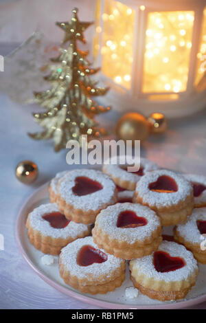 Gros plan sur linzer cookies de Noël traditionnel rempli de confiture rouge sur fond clair avec des décorations de Noël Banque D'Images