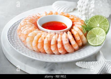 Gros plan sur couronne de crevettes avec sweet chili sause avec l'aneth et des tranches de citron vert Banque D'Images