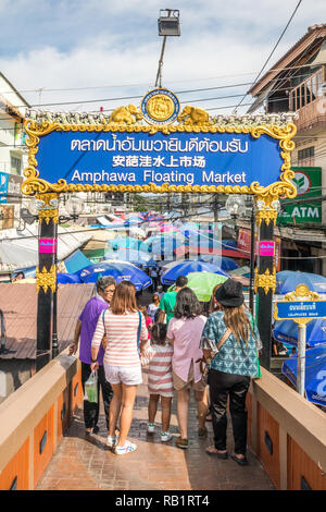 Amphawa, Thaïlande - 7 octobre 2018 : les touristes crossing bridge en vertu de l'inscription en Anglais, thaïlandais et chinois, un marché a lieu chaque semaine. Banque D'Images