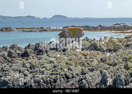 ​Moraine a déposé, le gros rocher, granit, roche, pierre, a déposé, avant-plan. Le ​Isle d'Iona, Port Beag Na Sligineach, Son d'Iona, Hébrides intérieures. Mull sur l'horizon. Côte ouest de l'Écosse.​ Banque D'Images