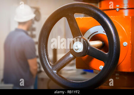 Power Station. travailleur homme ingénieur au casque et shirt twist le tuyau de gaz de mise au point sélectionnée vanne Banque D'Images