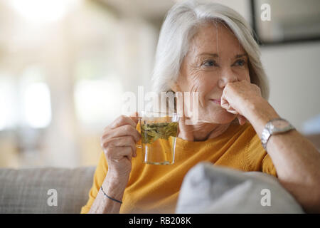 Belle femme senior à la maison avec une tasse de thé en feuilles Banque D'Images