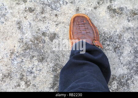 Jambe droite homme Chaussure en cuir marron et marche sur le plancher de béton Banque D'Images
