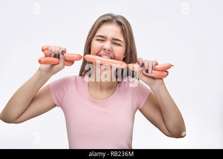 Jeune femme tenez set de saucisses entre les dents. Elle les tenir avec les mains. Isolé sur fond blanc. Banque D'Images