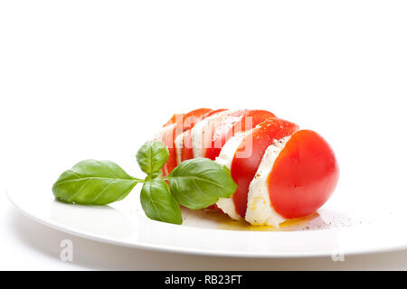 Le démarreur italien appelé "Insalata Caprese" est un mélange de tomates en tranches de fromage mozzarella, basilic et assaisonné de sel, poivre et huile d'olive. Banque D'Images