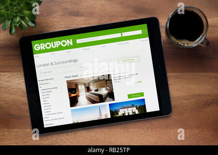 Le site internet de Groupon est vu sur un iPad tablet, sur une table en bois avec une machine à expresso et d'une plante (usage éditorial uniquement). Banque D'Images