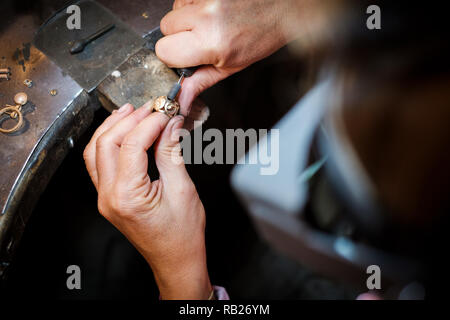 Bijoutier polit une bague en or sur un vieux workbench dans un authentique atelier de joaillerie Banque D'Images