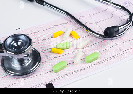 Stéthoscope médical étendu sur cardiogramme graphique avec tas de comprimés libre. La prévention de la protection de la santé de soins en cardiologie et de l'aide. Vie saine ou insur Banque D'Images