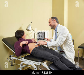 Un gynécologue faisant une échographie procédure sur un heureux fortyish man femme enceinte avec une échographie médicale. Banque D'Images