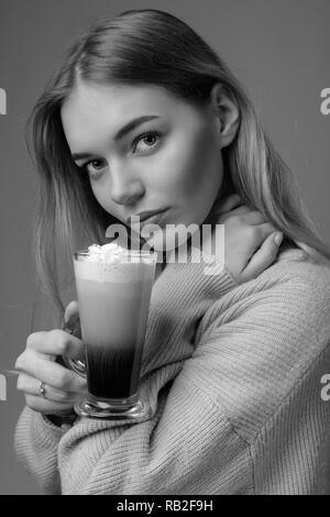 Jolie jeune femme avec un café irlandais. Belle blonde dans un chandail avec une grande tasse de café avec de la crème. Banque D'Images