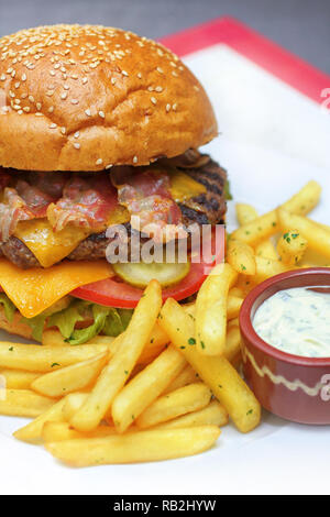 Burger fraîchement préparé avec du boeuf haché, fromage cheddar et frits avec des frites Banque D'Images