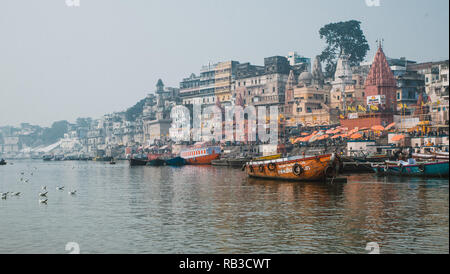 Paysage de la vieille ville de Varanasi dans le nord de l'Inde. Prendre une excursion en bateau sur le fleuve saint Ganges appelé ganga. Bâtiments et bateaux Orange Banque D'Images