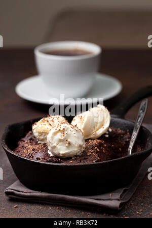Brownie avec une glace à la vanille dans une casserole, une tasse de café sur un fond brun Banque D'Images
