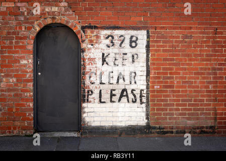 Veuillez rester à l'écart peint main signe sur brique rouge à côté d'une entrée voûtée Banque D'Images