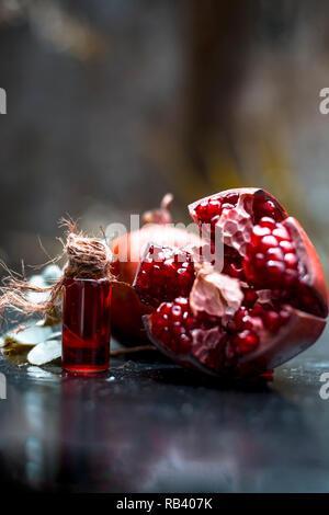 Close up d'essence de Grenade Grenade bio avec des matières sur la surface en bois en bouteille transparente utilisée dans les boissons à saveur,spa,etc. Banque D'Images