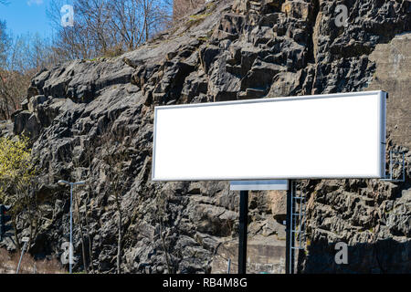 Blank white billboard on city street. Dans l'arrière-plan et de la rue des roches. Des maquettes. Poster sur rue à côté de route. L'espace vide pour le texte. Copier l'espace. Banque D'Images