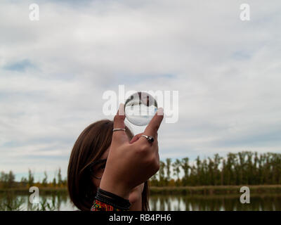 Une jeune femme avec une boule de cristal dans sa main sur le bord d'une rivière en automne Banque D'Images