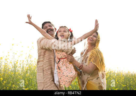 Les parents de l'Inde rurale avec sa fille s'amusant dans le colza champ agricole Banque D'Images