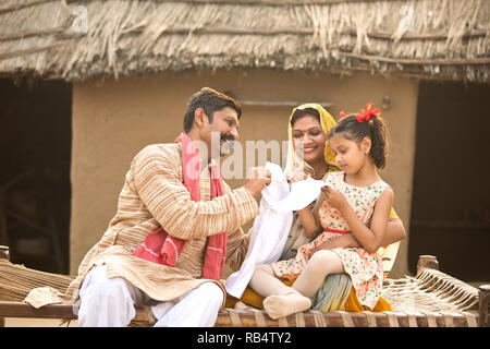 Les parents de l'Inde rurale nouvelle robe de don pour petite fille au village Banque D'Images