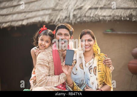 Portrait de famille rurales indiennes montrant nouveau téléphone mobile à village Banque D'Images