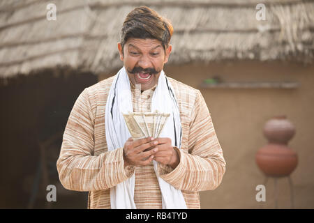 Succès farmer holding Indian Rupee notes et crier au village Banque D'Images