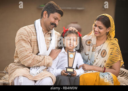 Fiers parents indiens avec little daughter holding Trophy, en uniforme d'au village Banque D'Images