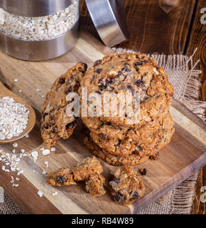 Vue de dessus d'une pile de biscuits à l'avoine et aux raisins sur une planche en bois avec des flocons d'avoine en arrière-plan Banque D'Images