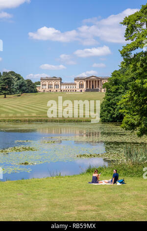 Un jeune couple appréciant un pique-nique au bord du lac à Stowe House Gardens, Buckinghamshire UK Banque D'Images