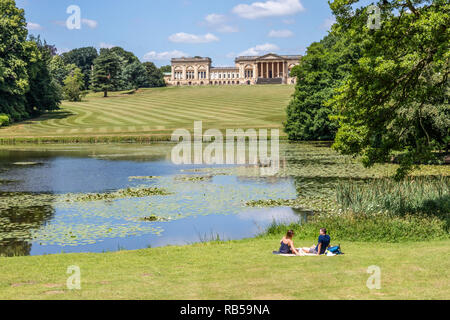 Un jeune couple appréciant un pique-nique au bord du lac à Stowe House Gardens, Buckinghamshire UK Banque D'Images