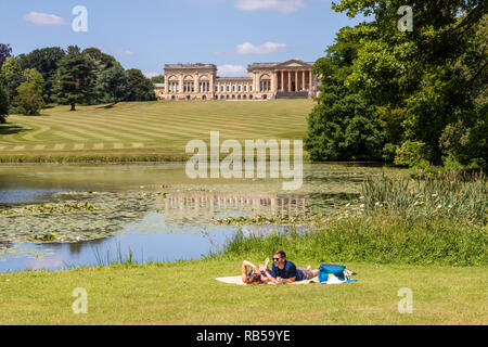 Un jeune couple appréciant un pique-nique au bord du lac à Stowe House Gardens, Buckinghamshire UK Banque D'Images