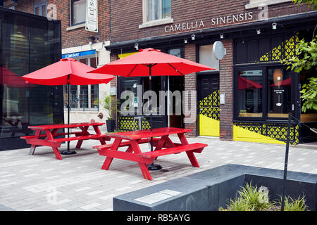 Pique-nique en bois rouge des bancs et tables de pique-nique avec des parasols sur la rue en face d'un café à Montréal, Canada. Banque D'Images