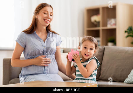 Mère et fille enceinte avec piggy bank Banque D'Images