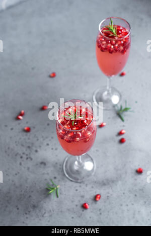 Champagne Cocktail Grenade Mimosa (cocktails sans alcool) au romarin sur fond de béton, de copier l'espace. Mimosa boisson pour la Saint-Valentin ou autres jours fériés. Banque D'Images