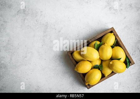 Citrons avec des feuilles vertes dans l'encadré sur fond noir en blanc, vue du dessus, copiez l'espace. Agrumes citrons frais biologiques. Banque D'Images