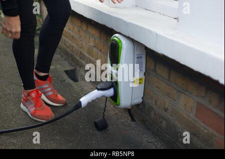 Charge électrique femme son SUV en dehors de sa chambre Banque D'Images