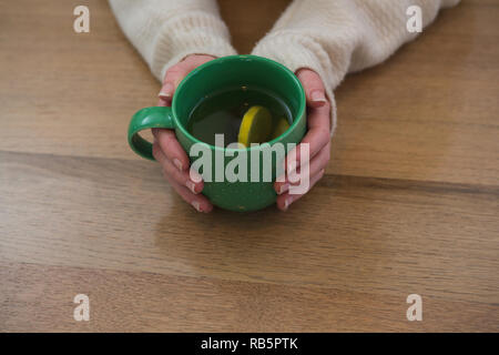 Femme tenant une tasse de thé au citron à la maison Banque D'Images