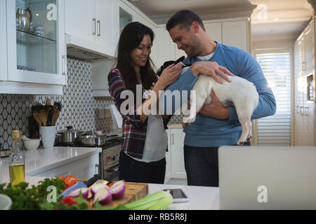 Couple de jouer avec leur chien de compagnie dans la cuisine Banque D'Images