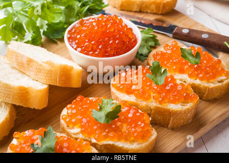 Sandwiches avec red caviar de saumon sur une planche de bois. Haut de table blanc Banque D'Images