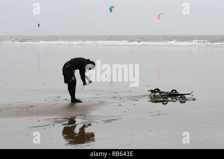 Un kite surfer vérifie ses lignes au cours d'une session au repos, la baie de Porthcawl, dans des conditions de vent sur la côte sud du Pays de Galles. Banque D'Images