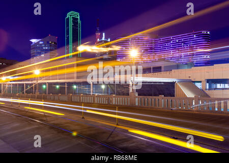 Des sentiers de lumière de se déplacer sur le tramway Houston street avec la ville de Dallas en arrière-plan Banque D'Images