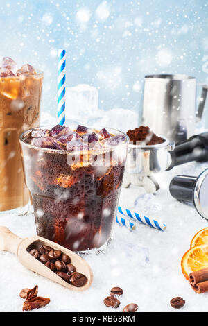 Boisson d'hiver café glacé dans un verre et de la glace à la crème de café dans un grand verre entourée de glace, les grains de café, portafilter, infalsifiable, pot à lait et Vario Banque D'Images