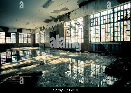 Intérieur de l'hôpital psychiatrique abandonné avec des fenêtres cassées et de l'eau inondation sur marbre Banque D'Images