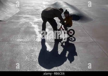 Denver, Colorado - Adam Hjermstad père aide son fils de quatre ans, Adam Jr., à monter son vélo équilibre dans un skatepark. Banque D'Images