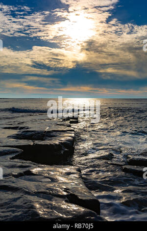 Photographie de paysage en orientation portrait d'un rebord en saillie dans le lavage humide sous la mer ciel dynamiques prises sur la baie de Kimmeridge, Dorset, UK. Banque D'Images