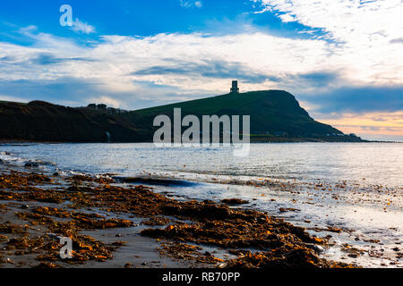 Photographie de paysage prises sur la plage couverte d'algues sur la baie avec une silhouette d'falaise et tour en arrière-plan sous ciel dynamique. Prise à Kimmeridge b Banque D'Images