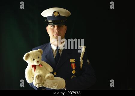 Marin de la Garde côtière canadienne Brian McCrum, membre de la Garde côtière des États-Unis, la garde d'honneur de cérémonie est titulaire d'un ours en peluche tout en posant pour un portrait à l'édifice fédéral de Portsmouth à Portsmouth, en Virginie, le 14 décembre 2016. McCrum posées pour aider à faire prendre conscience aux lecteurs de la Garde côtière Station de jouets par Milford Haven dans Milford Haven, Virginia. Banque D'Images