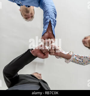 Vue de dessous de trois personnes cognant leurs poings dans la célébration de leur succès. Banque D'Images