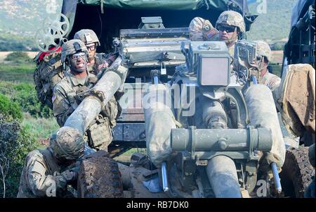 Les artilleurs de l'Armée américaine affecté à une batterie, 4e bataillon du 319e Régiment d'artillerie aéroporté, 173e Brigade aéroportée, emportez un obusier M777 dans le cadre de l'exercice de l'été 16 Tempest à Capo Teulada en Sardaigne, Italie, 2 décembre 2016. Tempête d'été 16 est un exercice multinational visant à améliorer et développer une compréhension commune des opérations de tir réel, en utilisant les systèmes d'armes et tactiques des procédures. Banque D'Images