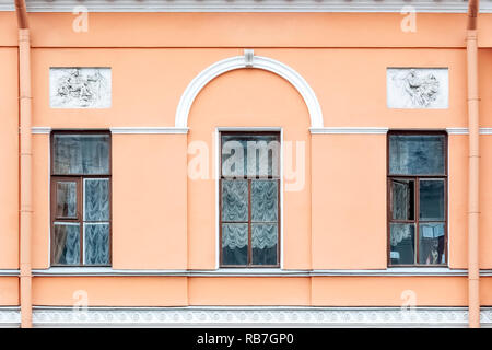 Trois fenêtres rectangulaires avec un arc et un bas-relief sur l'arrière-plan d'un mur rose. À partir d'une série de fenêtres de Saint-Pétersbourg. Banque D'Images