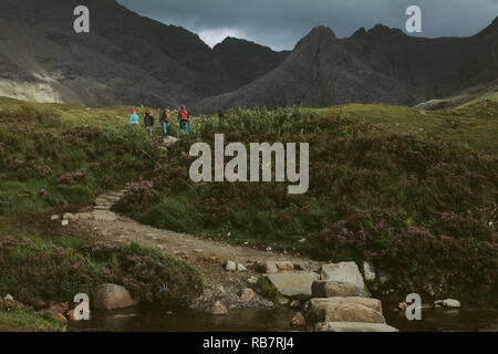 Tourits explorer le conte de piscines sur l'île de Skye, en face de la chaîne de montagnes Cuillin, UK Banque D'Images